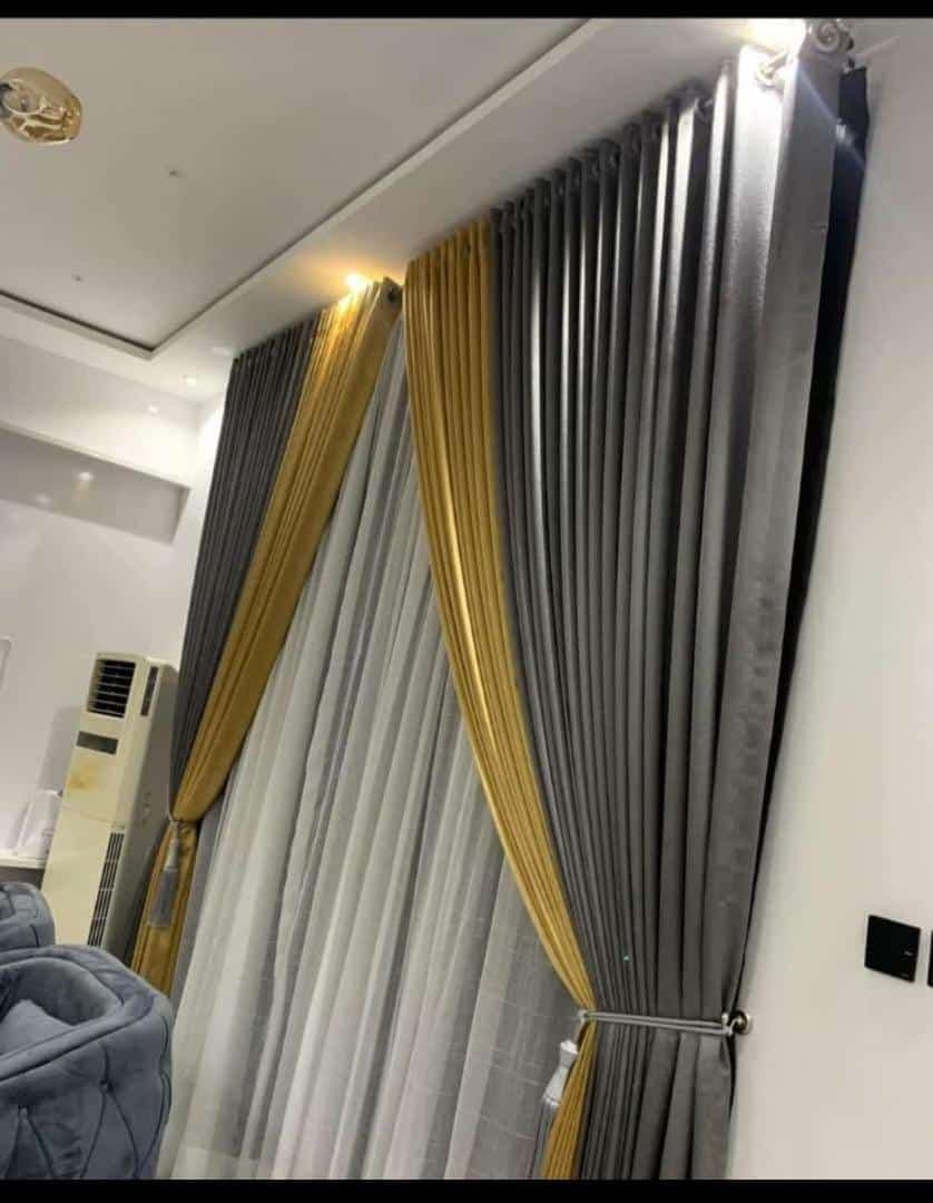 Grey and gold layered curtains with sheers, tied back beside a window